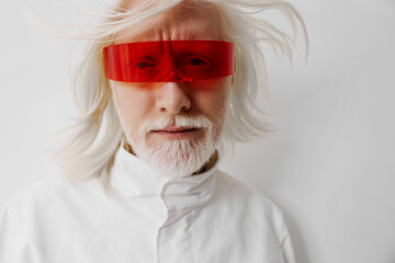 Elderly man with long white hair wearing bold red futuristic sunglasses against a plain white...