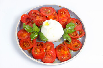 Tomatoes with a ball of burrata on a white background.