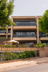 Fototapeta premium Modern apartment building with large balconies and greenery. structure features a contemporary design and is surrounded by trees