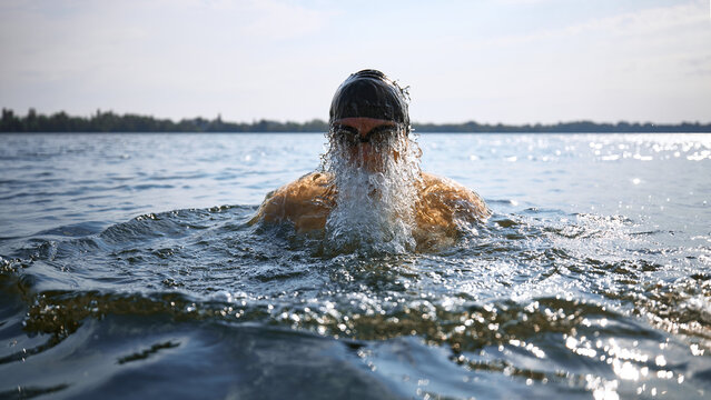 Senior swimmer emerging from water with intense strength. Concept of aging vitality, mature athleticism, endurance training, senior fitness campaigns, and health awareness visuals.