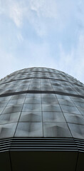 Modern skyscraper facade with curved glass geometry. Symmetrical patterns reflect light and sky....