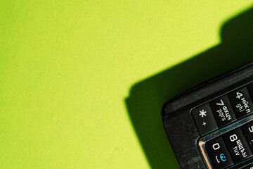 Close-up of retro mobile phone keypad on neon green background with sharp shadows. High quality...