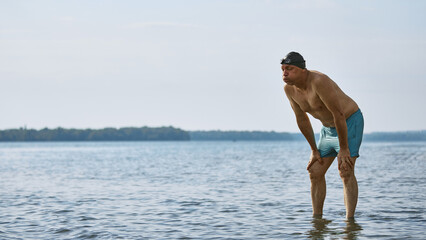 Exhausted mature swimmer leaning forward and puffing cheeks. Concept of fatigue after workout,...