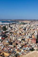 Obraz premium Aerial view of Alicante showcasing vibrant urban architecture, with a blend of traditional and modern buildings against a clear blue sky, highlighting the dynamic city life.