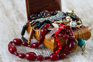 An antique wooden jewelry box filled with necklaces and costume jewelry