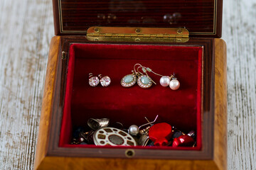 An antique wooden jewelry box filled with necklaces and costume jewelry