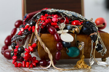 An antique wooden jewelry box filled with necklaces and costume jewelry