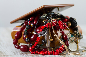 An antique wooden jewelry box filled with necklaces and costume jewelry