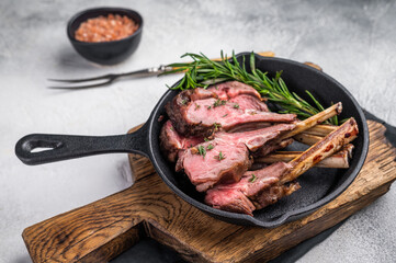 Roast lamb chops, mutton meat cutlets in a skillet. grey background. top view