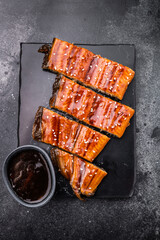 Unagi kabayaki eel, japanese grilled fish fillet with sauce. black background. top view