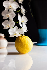 Still life of lemon on marble with white orchid in the background
