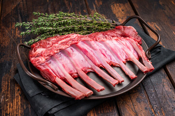 Fresh rack of lamb, raw mutton meat for chops steaks on steel tray. wooden background. top view