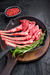 Ready for cooking Raw lamb meat chops, fresh mutton cutlets in a pan. black background. top view