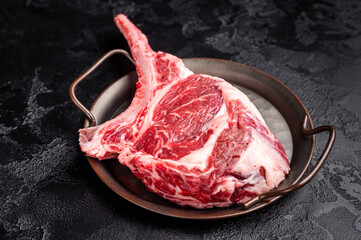 Raw tomahawk steak with marbling, fresh rib eye with bone. black background. top view