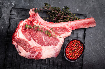 Uncooked tomahawk steak, raw black angus beef rib eye with bone. black background. top view