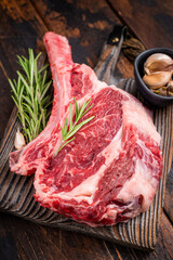 Raw Tomahawk beef steak, fresh black angus ribeye with bone on wooden board. wooden background. top view