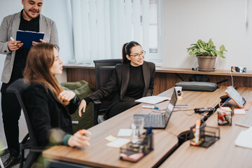 Business team members discussing ideas and strategies in a collaborative work setting. The meeting takes place in a professional yet relaxed office, featuring modern technology and office decor.