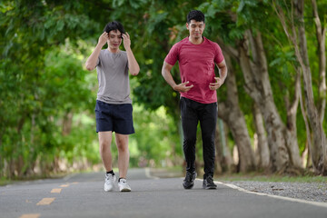 Happy active men jogging outdoor in nature green park. Gay couple exercising running together in the morning. Healthy lifestyle of two young people is exercise in countryside. Gay couple enjoyment.