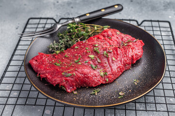 Marinated Skirt machete  steak, raw beef meat with thyme and spices on plate. grey background. top...