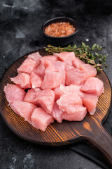 Sliced turkey fillet cubes, diced poultry breast meat. black background. top view