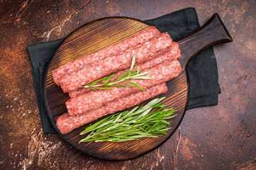 Fresh raw beef and lamb meat kebabs sausages  on wooden board. brown background. top view