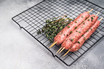 Raw kofta or lula kebabs skewers from mince lamb and beef meat on Skewer. grey background. top view