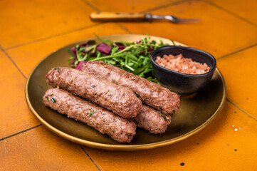 Grilled kofta or lula kebabs from mince lamb and beef meat on a plate with salad. brown background. top view