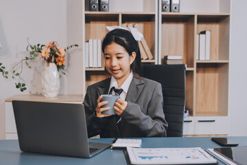 Asian Businesswoman Using laptop computer and working at office with calculator document on desk,...