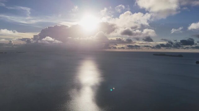 Drone flyover of the vibrant blue ocean and scenic islands of Palau with the sun beginning to set in the horizon. Cinematic aerial drone shot.