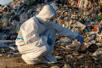A dedicated environmental worker kneels beside a polluted area in a landfill, carefully collecting...