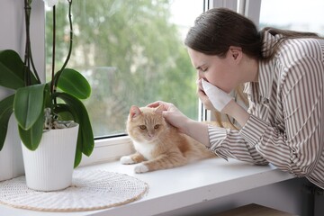 Woman suffering from allergy with her cat near window at home