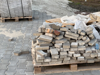 Stacked concrete bricks rest on wooden pallets at a construction site, showing various shapes and...