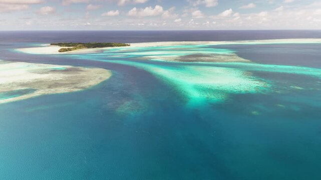 Cinematic aerial flyover revealing the glowing waters and sandy coastal shores near Palau. Wide cinematic drone shot.