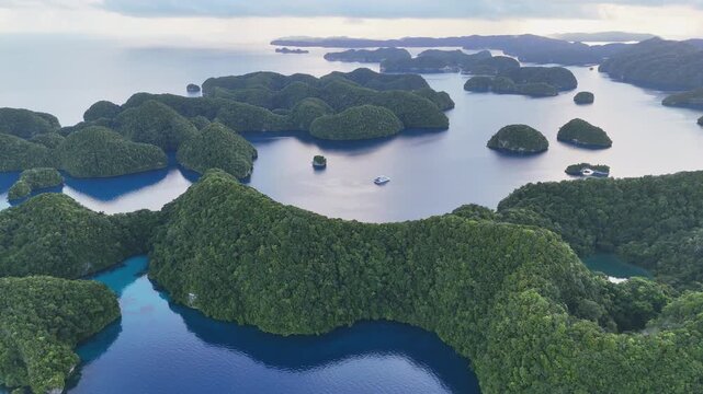 Cinematic aerial drone shot orbiting the vivid aqua ocean and green-covered terrain of Palau. Wide cinematic orbiting drone shot.