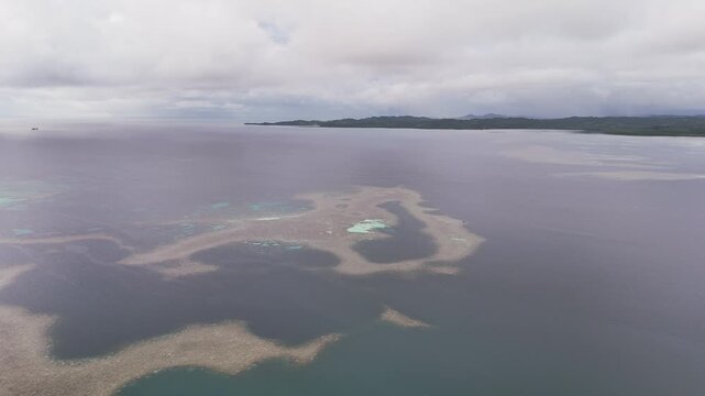 Aerial cinematic drone shot revealing coastal tropical waters and distant islands in Palau. Wide cinematic drone shot.