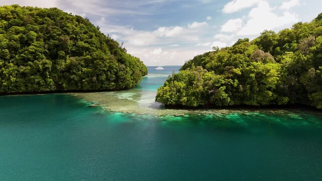 Cinematic flyover drone shot revealing the pristine turquoise sea and lush islets off the coast of Palau.