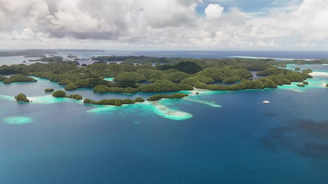 Captivating drone footage sweeping across the pristine turquoise sea and lush islets around Palau. Wide cinematic aerial shot.