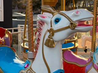 A beautifully crafted carousel horse stands proudly at an amusement park, surrounded by colorful...