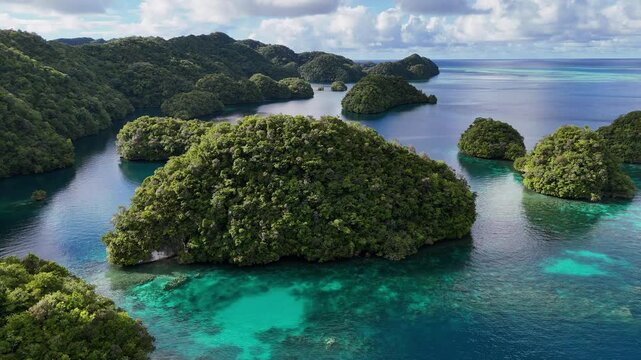 Scenic drone shot circling and revealing the pristine turquoise sea and lush islets of Palau. Orbiting drone shot of a large island of Palau.