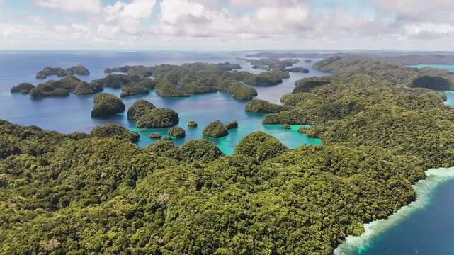 Elegant drone shot panning across the sparkling marine blue and islands in Palau. Wide panning drone shot.