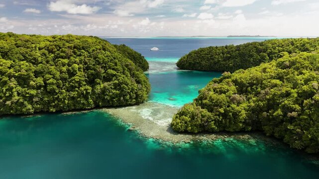 Epic aerial clip gliding through a divide in the islands around the serene turquoise coastline and small tropical islands in Palau. Cinematic aerial drone shot.