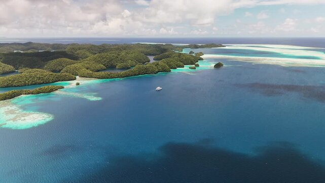 High-quality drone shot of clear aqua ocean and green-covered terrain of Palau. Boats in the lagoon.