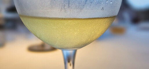 A glass of chilled white wine against a blurred background in a restaurant on the Ligurian Riviera in the summer of 2025.