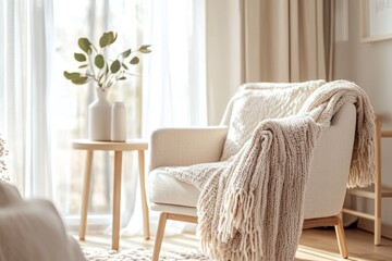 A white chair with a white blanket draped over it sits in front of a window