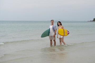 Happy young couple with surfboards enjoying a tropical beach holiday by the turquoise sea on a paradise island. capturing the lifestyle of happy people on a relaxing holiday by the ocean. baech.