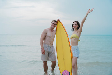 Happy young couple with surfboards enjoying a tropical beach holiday by the turquoise sea on a paradise island. capturing the lifestyle of happy people on a relaxing holiday by the ocean. baech.