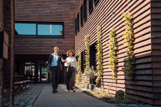 Business professionals walking outdoors discussing plans at modern building