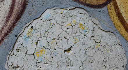 Close up of cracked and peeling paint on a wall with visible layers and color variations present
