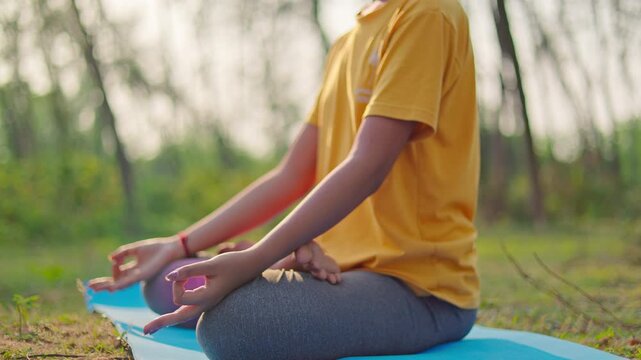 close up shot of a woman in padmasana pose meditating with closed eyes at outdoor during sunrise, relaxation, self care, India.