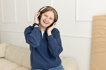 Woman with headphones at home on the couch. Listening to a podcast or live broadcast. Rest at home....